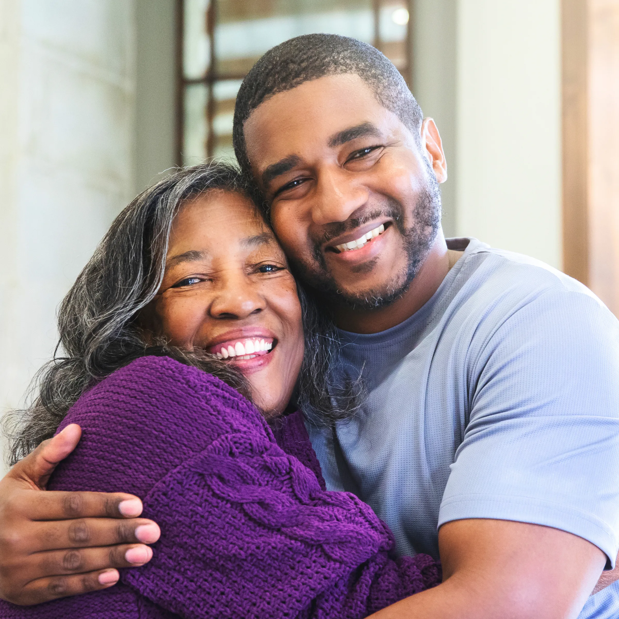 Man wearing a grey shirt hugging woman wearing purple sweater