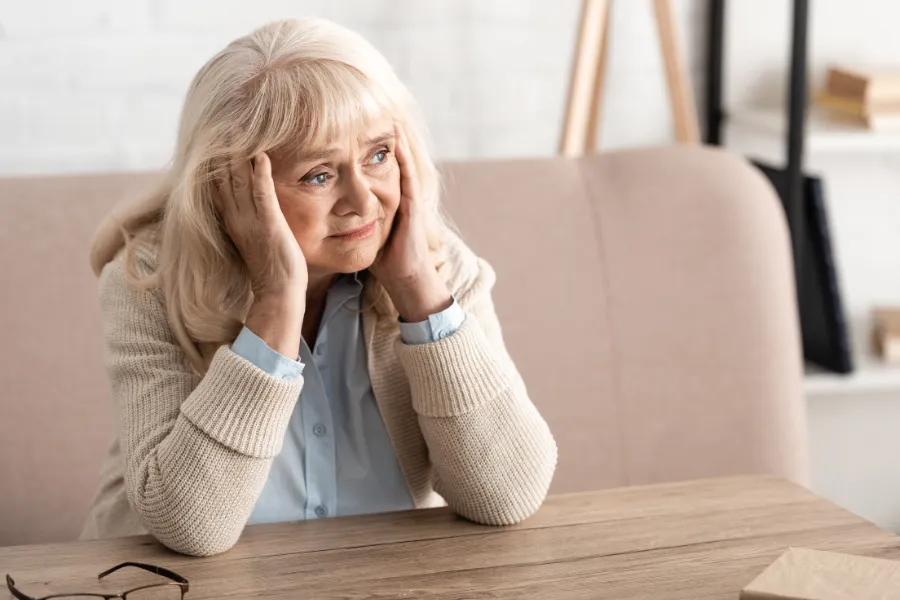 Older woman sitting at a table in thought
