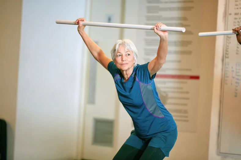 Active senior woman exercising with a fitness bar in an independent living community in Winter Haven